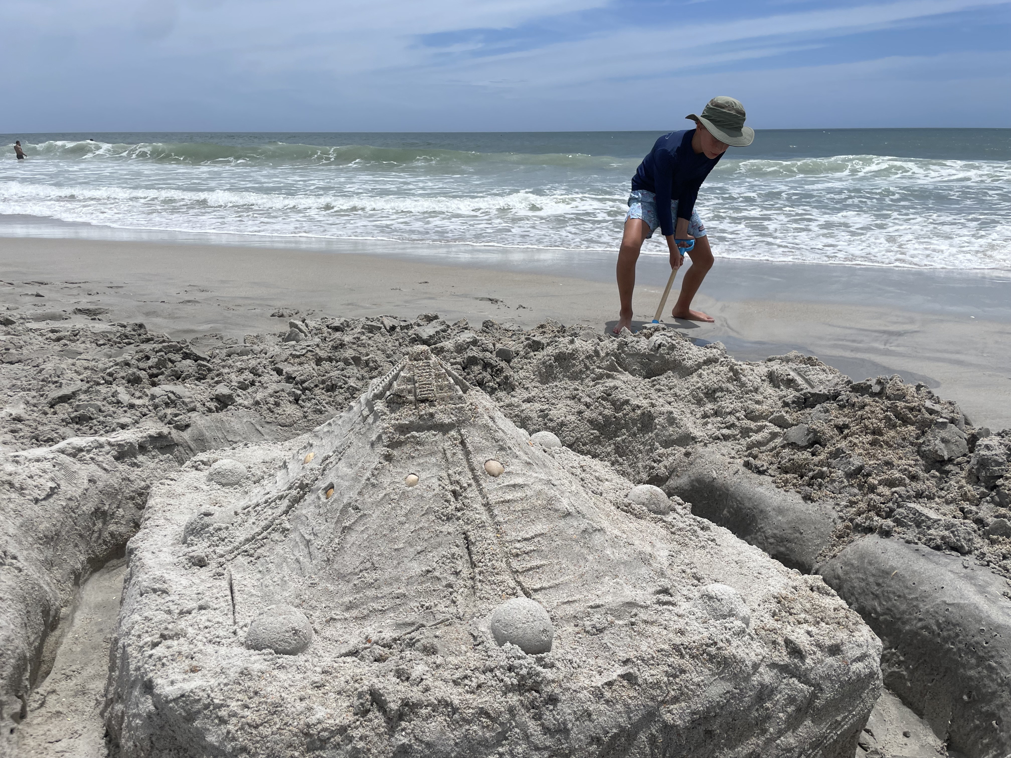 Child playing with sand at the beach - Young boy digging sand on the beach, building sand castle, near ocean